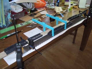 I clamped the inverted track against the table and straight edge to allow focusing on the position of the spans as they are glued in position.